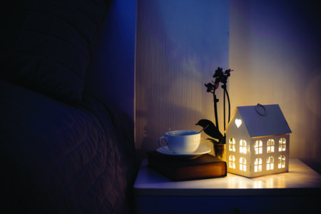 Cozy evening bedroom interior, cup of tea and a night light on the bedside table.&hellip;